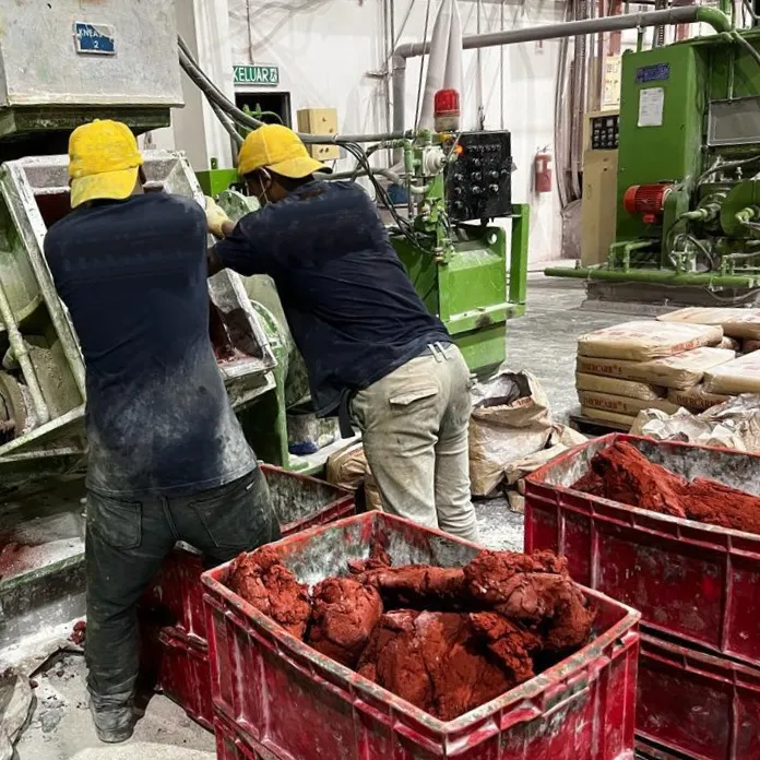 Team of foreign workers performing demanding production tasks in a manufacturing facility, ensuring compliance with international recruitment and occupational safety standards.